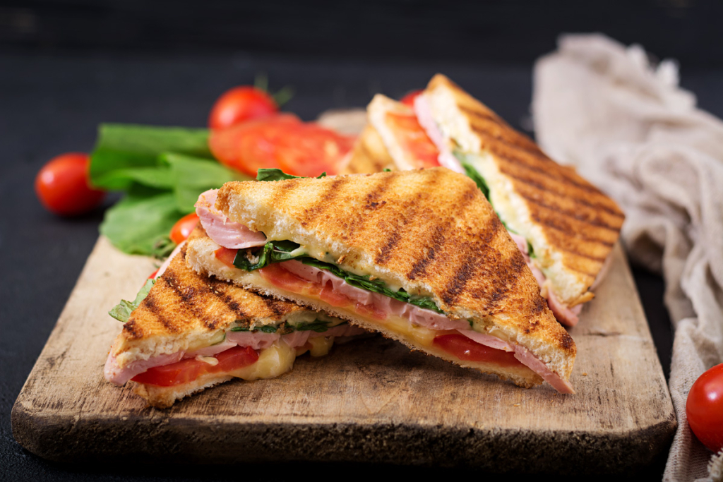 Toasted sandwiches with ham, chese, tomatoes, and lettuce leaves.