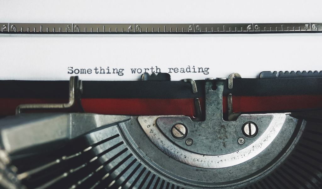 The photo shows a typewriter and a piece of paper with the words "Something worth reading."