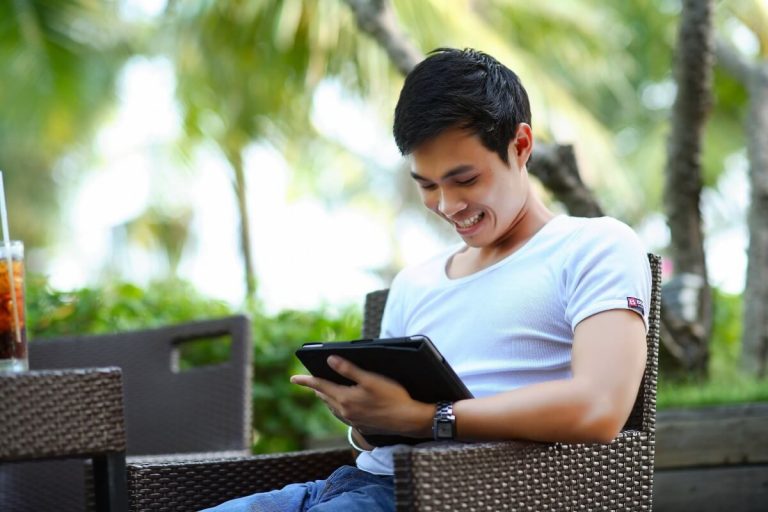 Man is Using Tablet and Smiling.