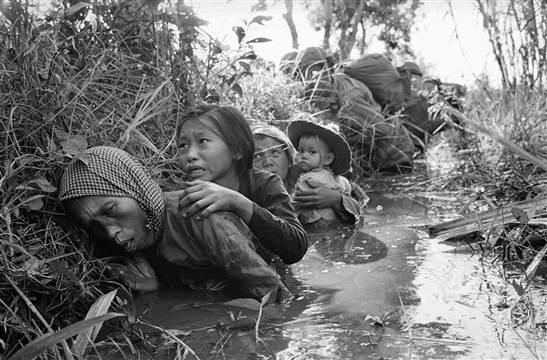 Women and children hiding from Viet Cong fire, 1966