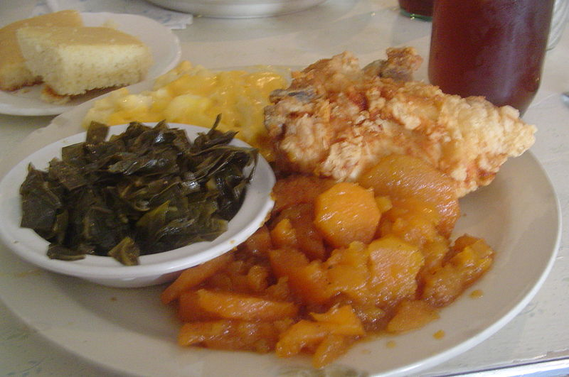 A traditional soul food dinner consisting of fried chicken, candied yams, collard greens, cornbread, and macaroni and cheese