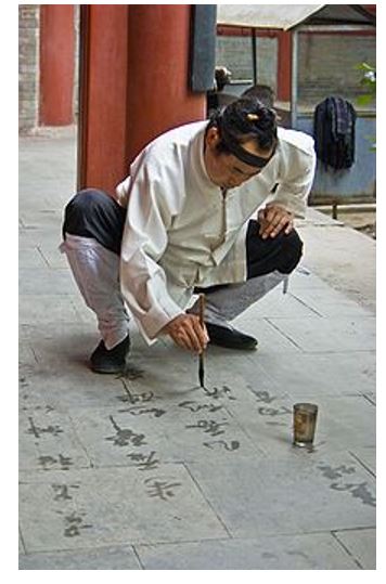 Taoist monks are practicing writing Chinese calligraphy using brush and ink on stones