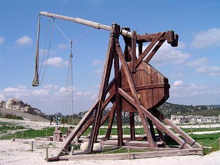 A photograph of the external structure of the trebuchet shows the presence of the long arm of the lever, the place for the projectile, and the triggering mechanism